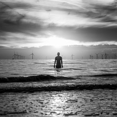 Antony Gormley 'nin Eylül 2021' de gün batımında görmek için başka bir yere bakan bir Demir Adam heykelinin kare şeklindeki görüntüsü..