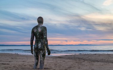 Eylül 2021 'de Liverpool yakınlarındaki Crosby Sahili' nde Antony Gormley 'nin başka bir yer sanat kurulumunun bir parçası olan Demir Adam' a yaklaşan gelgit..