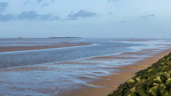 A multi image panorama of a channel of water snaking out of the Dee Estuary towards Hilbre Island in the distance seen on 1 January 2022 at West Kirby, Merseyside.