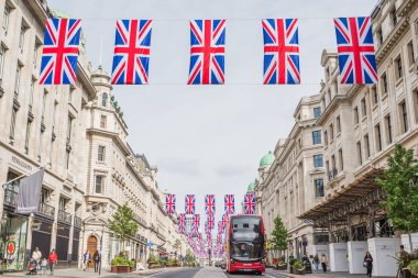Geleneksel kırmızı çift katlı Londra otobüsü, Londra 'nın Queens Platin Kutlamaları için hazırlandığı Mayıs 2022' de Union Jack bayraklarının altında Regent Caddesi boyunca ilerliyor..