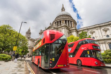 Mayıs 2022 'de Londra' nın göbeğindeki St. Pauls Katedrali 'nin önünden bir çift canlı kırmızı Londra otobüsü geçer..