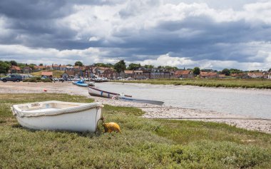 Small boats seen beached on the side of a channel of water at Blakeney in July 2022 on the North Norfolk coast.