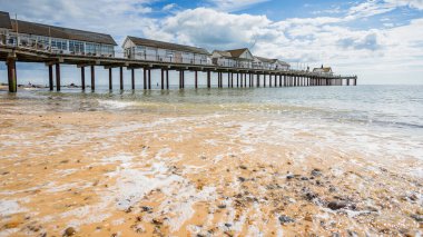 Suffolk sahilindeki Southwold plajındaki kum ve taşların üzerinden sular aktı. Temmuz 2022 'de rıhtımın yanında..