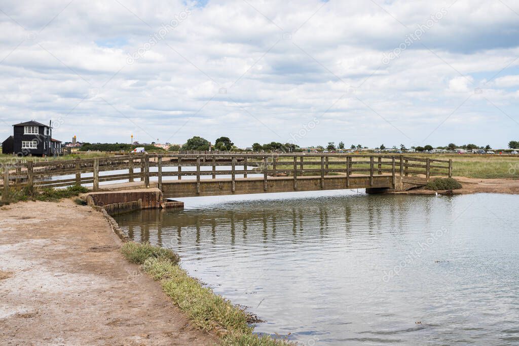 Walberswick footbridge pictured over a wide channel of water in Suffolk, popular for people to go crabbing.