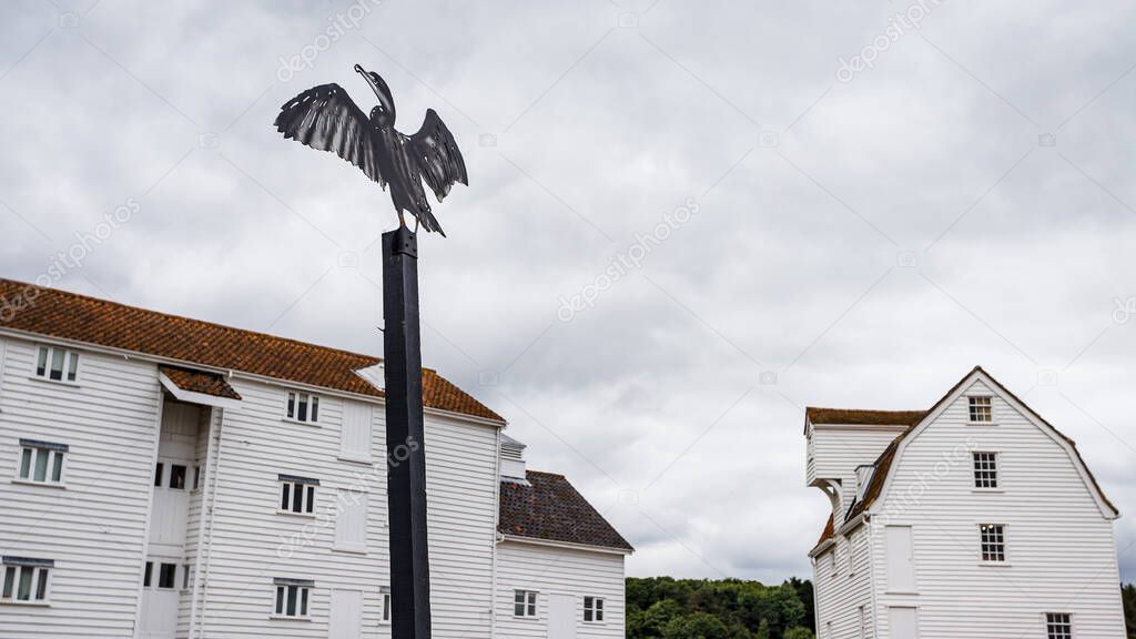 A cormorant sculpture seen under Woodbridge Tide Mill in Suffolk in July 2022 on an overcast morning.