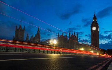 Red traffic trails captured at twilight in July 2022 as vehicles pass Westminster Bridge and towards Big Ben.