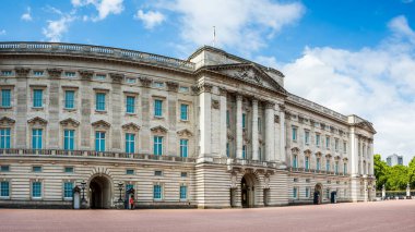 A multi image panorama of two soldiers in red coats and bearskin caps guarding Buckingham Palace in London during August 2022.