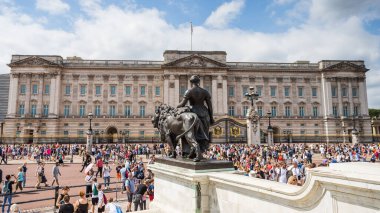 Letterbox crop of a lion on the Victoria Memorial facing Buckingham Palace in London in August 2022 surrounded by tourists who had been watching the Changing of the Guard ceremony.