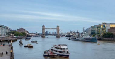 Tower Bridge illuminated behind HMS Belfast on the River Thames as the light fades one evening in August 2022 in London.