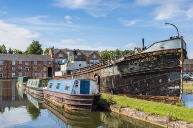 Varies canal barges of different ages and sizes pictured moored in Ellesmere Port, Cheshire in August 2022.
