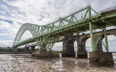 Silver Jubilee Bridge and Runcorn Railway Bridge pictured at low tide from the banks of the River Mersey in Cheshire.