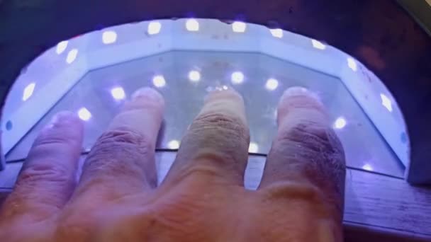 Ledランプ 美容室への訪問者は紫外線ランプの下で彼の手にベースジェルを乾燥させます ネイルケア マニキュア ツール 4Kビデオ — ストック動画