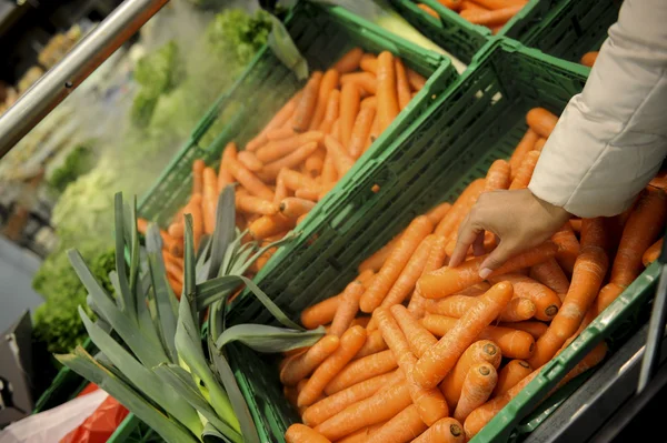 La donna compra carote e cibo al supermercato — Foto Stock