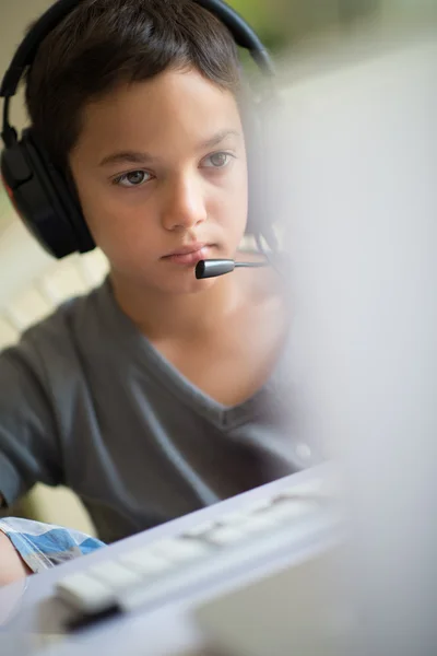 Niño jugando en el ordenador con auriculares — Foto de Stock