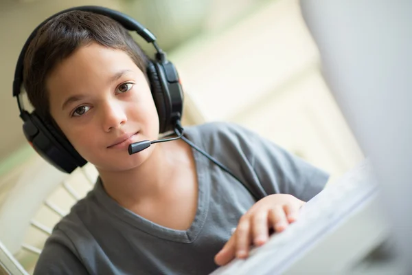 Kind spelen op de computer met een hoofdtelefoon — Stockfoto