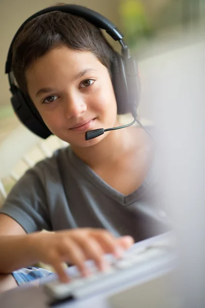 Niño jugando en el ordenador con auriculares — Foto de Stock