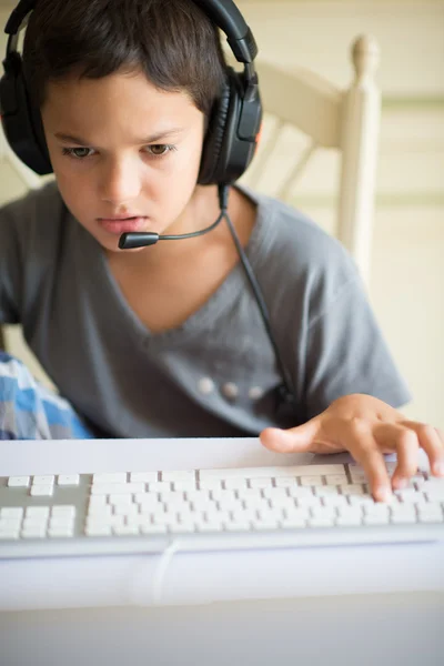 Niño jugando en el ordenador con auriculares — Foto de Stock