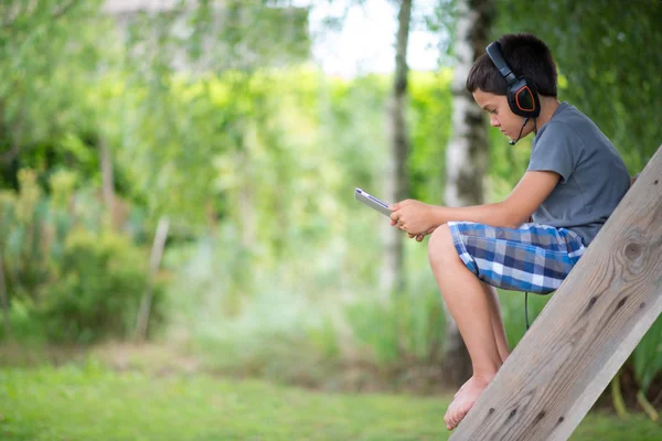 Child playing on the computer with headphones outdoor