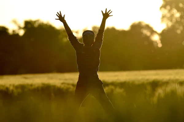 Kleiner Junge springt bei Sonnenuntergang in ein Weizenfeld — Stockfoto