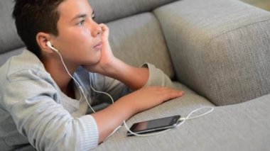 Genç genç müzik yaptığı telefon dinlemek bir kanepe üzerinde yalan