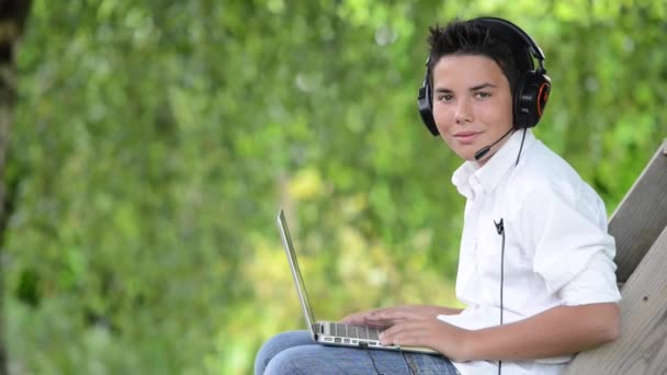 Joven adolescente acostado en un sofá escuchando música en su teléfono — Vídeo de stock