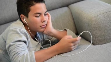 Genç genç müzik yaptığı telefon dinlemek bir kanepe üzerinde yalan