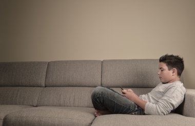 genç çocuk evde telefon ile kanepede yatan