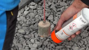 İşçi asfaltta bir noktayı floresan sprey boyayla işaretliyor.