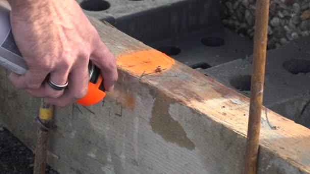 Trabalhador marca um ponto no asfalto com tinta spray florescente com um ajuste de linha de prumo — Vídeo de Stock
