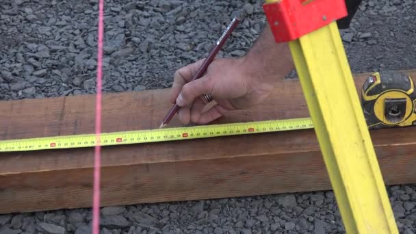 Builder doet metingen en plaatst tags op een bord — Stockvideo