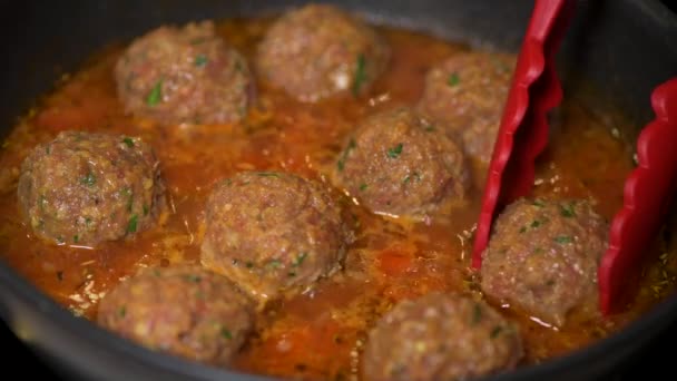 Cooking meatballs with tomato sauce in a pan — стоковое видео