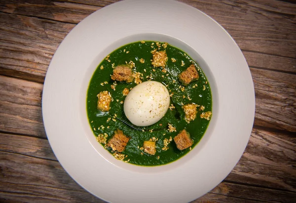 RECIPE FOR SOFT-BOILED EGG ON A COULIS OF TETRAGONE, BASIL, SAVORY AND PARSLEY SEASONED WITH CURCUMIN, SALT, ESPELETTE PEPPER, TOFU AND CROUTON TOASTED WITH SEZAME SEEDS. High quality photo