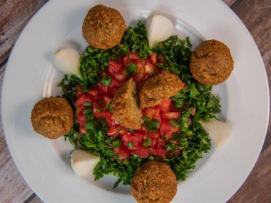 Vegetarian dish, falafel balls from spiced chickpeas with chopped parsley, fresh onions and tomato, tahini sauce, High quality photo