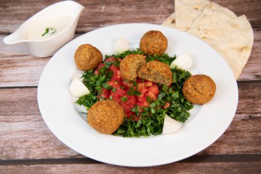 Vegetarian dish, falafel balls from spiced chickpeas with chopped parsley, fresh onions and tomato, tahini sauce, High quality photo