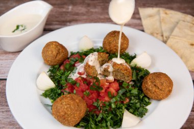 Vegetarian dish, falafel balls from spiced chickpeas with chopped parsley, fresh onions and tomato, tahini sauce, High quality photo