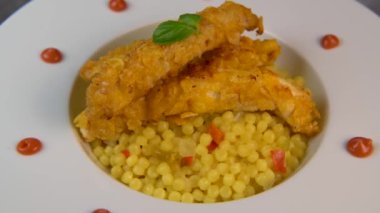 Recipe for chicken tenders with corn flakes and Italian Piombo pasta risotto and peppers on turntable. High quality video