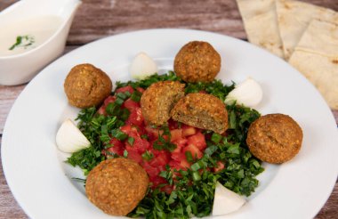 Vegetarian dish, falafel balls from spiced chickpeas with chopped parsley, fresh onions and tomato, tahini sauce, High quality photo
