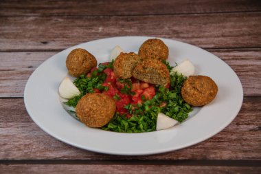 Vegetarian dish, falafel balls from spiced chickpeas with chopped parsley, fresh onions and tomato, tahini sauce, High quality photo