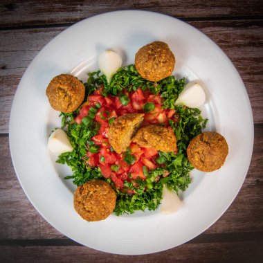 Vegetarian dish, falafel balls from spiced chickpeas with chopped parsley, fresh onions and tomato, tahini sauce, High quality photo