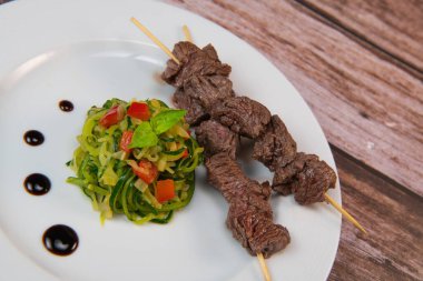 Skewer of beef mitre with curgettes and red pepper tagliatelle recipe. High quality photo