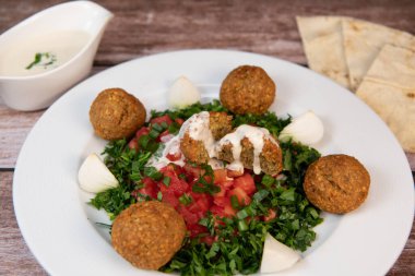 Vegetarian dish, falafel balls from spiced chickpeas with chopped parsley, fresh onions and tomato, tahini sauce, High quality photo