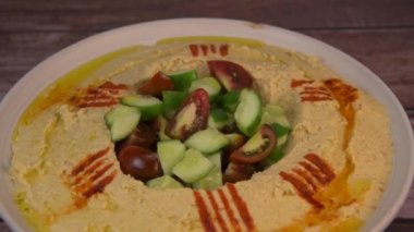 Homemade hummus with tahini plate with olive oil, parsley and paprika isolated on brown background. High quality video
