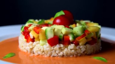 Vegan salad recipe based on bulgur with small vegetables, avocado, tomato, cucumber, pepper, nectarine fruit, tomato basil sauce and olive oil and lemon