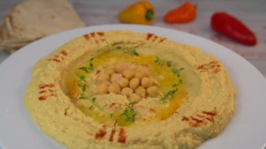 Homemade hummus with tahini plate with olive oil and paprika and pita isolated on brown background. High quality video 4k