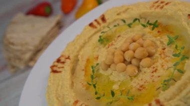 Homemade hummus with tahini plate with olive oil and paprika and pita isolated on brown background. High quality video 4k