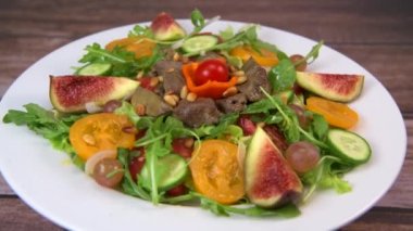 Recipe for fried chicken liver and gizzards with salad and tomatoes, cucumber, figs, grapes on a white plate, High quality video