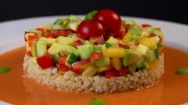 Vegan salad recipe based on bulgur with small vegetables, avocado, tomato, cucumber, pepper, nectarine fruit, tomato basil sauce and olive oil and lemon