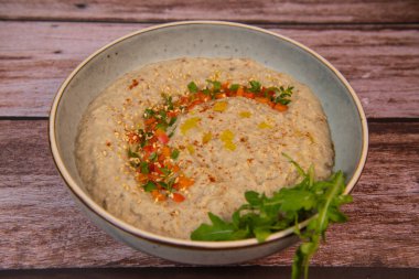 Traditional arabian eggplant dip baba ganoush with herbs and smoked paprika on a wooden background. High quality photo