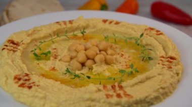 Homemade hummus with tahini plate with olive oil and paprika and pita isolated on brown background. High quality video 4k