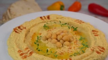 Homemade hummus with tahini plate with olive oil and paprika and pita isolated on brown background. High quality video 4k